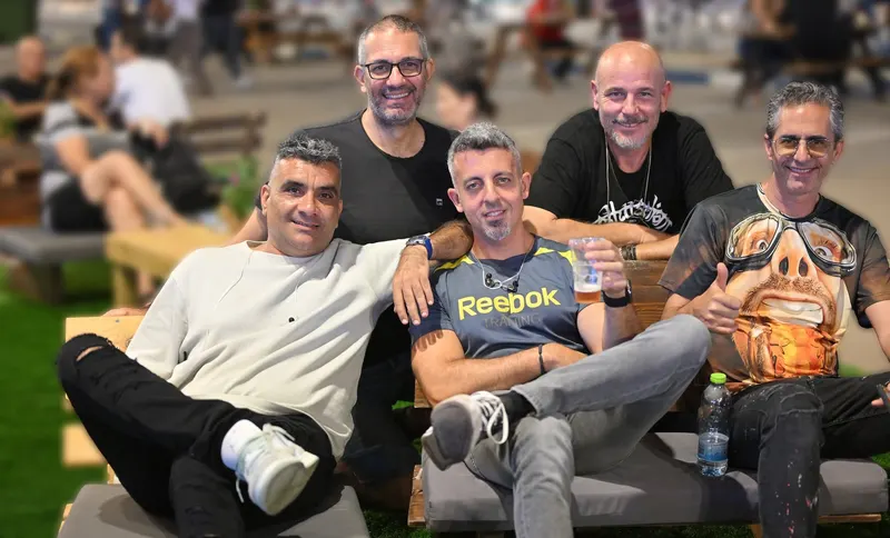 חברי להקת אקרופוליס יושבים יחד על הדשא באירוע חוצות